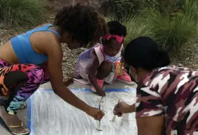  ??  ?? Artists Satya Wimbush, left, and Vanessa Frazier work with their niece to prime their space for a chalk drawing Saturday. Ashley Moser, who was pregnant, miscarried and was paralyzed from the waist down. Her 6-year-old daughter, Veronica Moser-sullivan, was killed. Her boyfriend Jamison Toews survived head wounds. The drawing above will honor the couple’s unborn child.