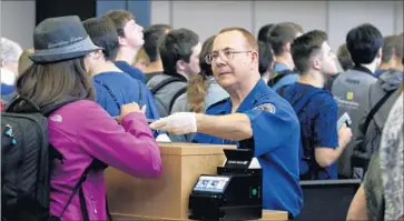  ?? Elaine Thompson Associated Press ?? A TSA AGENT checks ID in Seattle. Driver’s licenses in many states don’t comply with federal regulation­s.