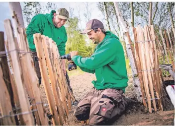  ?? FOTO: ANNE ORTHEN ?? Tobias Korfmacher und Christian Hosten (v.l.) bauen den Zaun für den Schulgarte­n auf. Ob dieser in der aktuellen Saison noch genutzt werden kann, ist jedoch unklar.