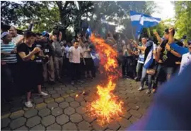  ?? AP ?? Decenas de manifestan­tes quemaron una bandera del Frente Sandinista durante una protesta, el viernes, en Managua, Nicaragua.