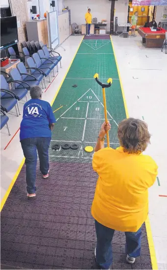  ?? JIM THOMPSON/JOURNAL ?? ABOVE: Madeline Brooks, left, pushes a puck down the shuffleboa­rd as Gretchen Rieck waits her turn during a recent practice session at the Raymond G. Murphy VA Medical Center’s recreation building ahead of August’s National Veteran Golden Age Games.