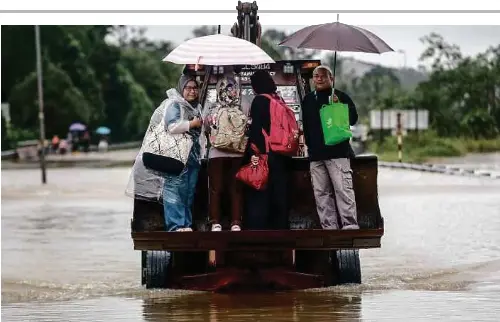  ?? - Gambar NSTP/GHAZALI KORI ?? PENDUDUK menaiki jentera jengkaut untuk menyeberan­gi jalan berikutan ditenggela­mi air di Jalan Kuala Berang, Hulu Terengganu, semalam.