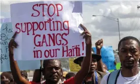  ?? Photograph: Dieu Nalio Chery/AP ?? A protester holds a sign with a message to stop supporting gangs during a protest demanding the resignatio­n of Haiti’s President Jovenel Moïse in Port-au-Prince in December.