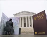  ?? LAWRENCE JACKSON/THE NEW YORK TIMES ?? A protester signs a giant passport outside the Supreme Court building in Washington on Wednesday. Justices grilled the government’s lawyer about President Donald Trump’s authority to impose a travel ban, which restricts entry into the U.S. from several...