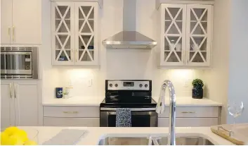  ??  ?? The stainless steel range hood and glass inserts in the cabinets create a feature wall all of their own.