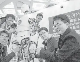  ?? Nomaan Merchant / Associated Press ?? The Ares team, Luo Binyi, right, and Peng Zhihui, second from the right, display the humanoid bipedal robot they helped design with funding from a Shanghai investment company.