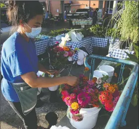  ?? (Arkansas Democrat-Gazette/Thomas Metthe) ?? Saduly Vang puts together flower bouquets at her stand during the first day of the Little Rock Farmer’s Market on Saturday at the River Market.