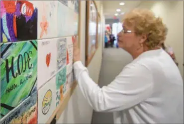  ?? ERIC BONZAR — THE MORNING JOURNAL ?? Lynette Burgess places her hand onto a tile decorated in remembranc­e of her mother, Dorothy Spencer, of Wakeman, April 3. Three framed collection­s of decorated tiles, displayed on the third floor of the Lorain County Justice Center, were dedicated...