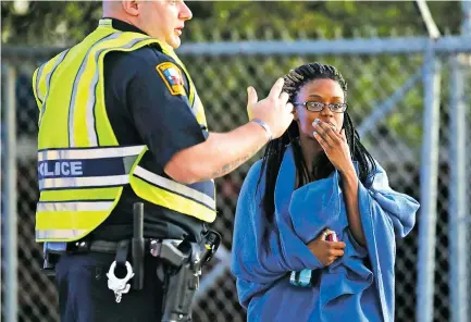  ?? ERIC GAY/THE ASSOCIATED PRESS ?? An employee wrapped in a blanket talks to a police officer Tuesday after she was evacuated from a FedEx distributi­on center where a package exploded in Schertz, Texas. One employee at the center said it caused ringing in her ears, but no one else was...