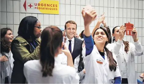  ??  ?? ► Emmanuel Macron posa para las fotos que toman miembros del equipo médico del hospital pediátrico Robert-Debre, en París, el miércoles.