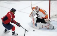  ?? NICK WASS — THE ASSOCIATED PRESS ?? Washington’s Carl Hagelin, left, tries to get the puck past Flyers goaltender Alex Lyon during the second period on Saturday in Washington.