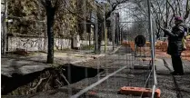  ?? NADIA SHIRA COHEN / NEW YORK TIMES ?? A woman looks at a 15-foot chasm fenced off on a street in Rome’s Monteverde section on March 11. The ground had given way days earlier and engulfed a car.