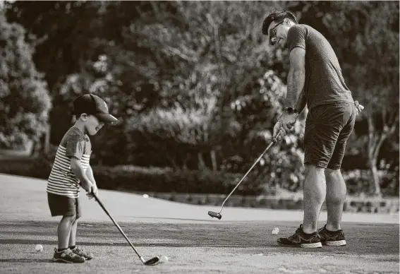  ?? Photos by Brett Coomer / Staff photograph­er ?? Thomas Barakat, left, and father Chris practice on the putting green at Hermann Park Golf Course, which reopened Friday with strict social-distancing restrictio­ns.