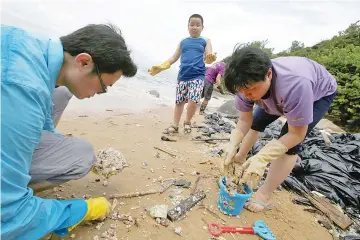  ??  ?? Volunteers collect crystallis­ed palm oil on a beach at Lamma Island in Hong Kong, China. — Reuters photo