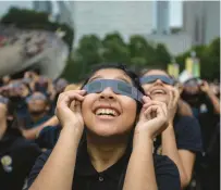  ?? ALEXANDRA WIMLEY/CHICAGO TRIBUNE ?? Students from Muchin College Prep react as the solar eclipse emerges from behind clouds in Millennium Park in Chicago on Aug. 21, 2017.