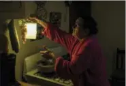  ?? DENNIS M. RIVERA PICHARDO — THE ASSOCIATED PRESS ?? Marta Bermudez Robles, 66, hangs a lamp in her kitchen in Adjuntas, Puerto Rico, at her home that is still with electricit­y since Hurricane Irma and Maria. The only power Bermudez and her husband have had for 10 months is courtesy of a neighbor who...