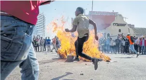  ?? PHOTOS BY EPA ?? LEFT
People gather around a fire on a street during a protest against polling results in Harare, Zimbabwe, on Wednesday.