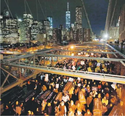  ??  ?? Protesters rally against a grand jury’s decision not to indict the police officer involved in the death of Eric Garner. They were carrying a collection of mock coffins in the eastbound traffic lanes of the Brooklyn Bridge. Jason DeCrow, The Associated...