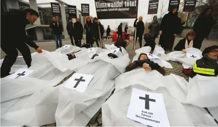  ?? (Fabrizio Bensch/Reuters) ?? GERMAN CAMPACT (Campaign and Action) activists, playing the roles of victims of natural disasters, take part in the protest against the climate change in Berlin Thursday. The slogan on the banner reads ‘Climate change kills.’