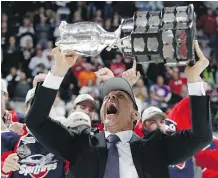  ?? DENNIS PAJOT/GETTY IMAGES ?? Spitfires head coach Rocky Thompson, a former Flames player, lets out a primal scream as he hoists the trophy after his team won the Memorial Cup on Sunday in Windsor, Ont.