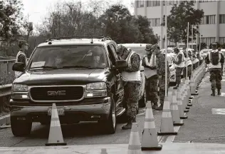  ?? Jae C. Hong / Associated Press ?? Members of the National Guard help motorists check in at a federally run COVID-19 vaccinatio­n site as cars lined up at the campus of California State University of Los Angeles.