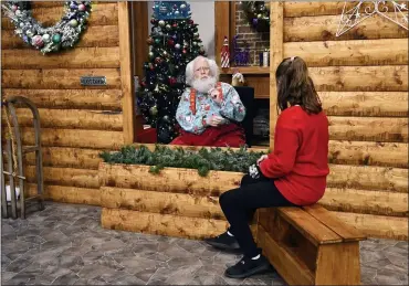  ?? JIM MONE — THE ASSOCIATED PRESS ?? Santa, Sid Fletcher, sits behind a glass barrier as he hears Kendra Alexander of St. James, Minn., during her visit to The Santa Experience at the Mall of America in Bloomingto­n, Minn. Where allowed, some malls and big-box stores are offering Santa’s guests a choice of full contact or social distance. A microphone in the green plays picks up conversati­ons.