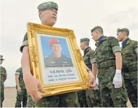  ?? AFP ?? Un soldado de la Marina tailandesa porta el retrato de Samarn Poonan, un exbuzo de la Armada que murió en medio del rescate.