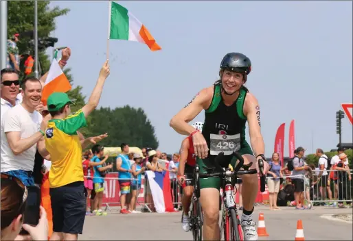  ??  ?? Eleanor Rooney is cheered across the finish line of the Slovakian Triathlon by club mates from the Mullaghmor­e Triathlon Club waving Irish flags.