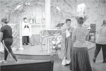  ?? ANNA WATTS/THE NEW YORK TIMES ?? The Rev. Juan Carlos Gonzalez gives communion to parishione­rs during a Spanish evening Mass on Aug. 19 at Our Lady of Lourdes Church in the Harlem neighborho­od of Manhattan.