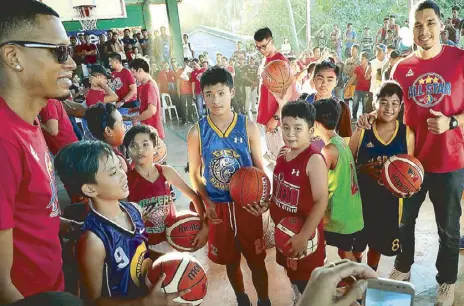  ?? PBA IMAGE ?? Young cagers receive basketball­s from PBA players Sonny Thoss and Rafi Reavis during a meet-and-greet session as part of the pro league’s community service during the PBA All-Star in Digos, Davao.