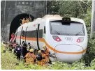  ??  ?? Rescue workers gather near one end of the derailed train in Taiwan