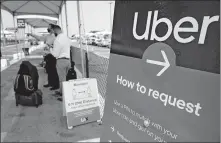  ?? ASSOCIATED PRESS FILE PHOTO] ?? Travelers request an Uber ride Aug. 20 at Los Angeles Internatio­nal Airport's LAX-it pick up terminal. A California ballot measure that would exempt Uber, Lyft and other app-based delivery drivers from being classified as company employees eligible for benefits and job protection­s led Tuesday in early vote counts. [DAMIAN DOVARGANES/
