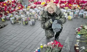  ?? EMILIO MORENATTI/ THE ASSOCIATED PRESS ?? An Ukrainian woman pays respect at the Independen­ce Square site where a friend was killed in clashes.