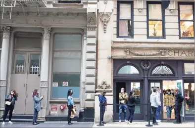  ?? Associated Press photos ?? A security guard, right, holds the door for Black Friday shoppers to leave as others wait to enter the Mackage store on Friday in the Soho neighborho­od of New York City.