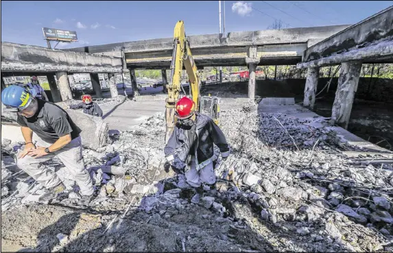  ?? JOHN SPINK /JSPINK@AJC.COM ?? Atlanta firefighte­rs remained on the scene putting out a smoldering fire Friday at the I-85 collapse site while constructi­on crews made their way into the zone to begin work. Three people were arrested, allegedly involved in starting the fire.