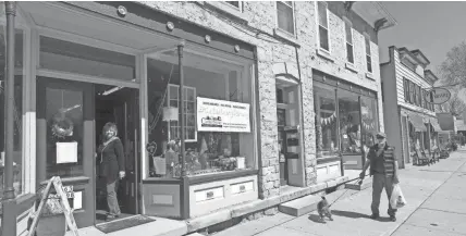  ?? PHOTOS BY MARK HOFFMAN / MILWAUKEE JOURNAL SENTINEL ?? A pedestrian passes Up the Creek while owner Debbie Lauer is in the doorway in downtown Cedarburg. The home decor and gift store just reopened after the coronaviru­s shutdown.