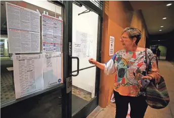  ?? CHERYL EVANS/THE REPUBLIC ?? Inspector Eileen Wendt looks Tuesday at a sign at a polling place in Chandler that was foreclosed before voting began. The site was eventually opened just after 9 a.m.