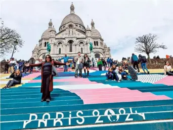  ?? AFP ?? Getting ready: People walk down the stairs painted in the colours of the upcoming Paris 2024 Olympics in front of the Sacre Coeur Basilica on top of the Montmartre hill in Paris.