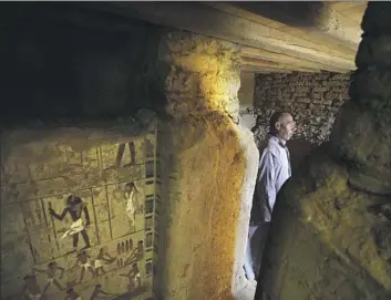  ?? Amr Nabil Associated Press ?? AN ANTIQUITIE­S guard watches over a recently discovered tomb near the Saqqara pyramids in Egypt. Artifacts unearthed beneath a stone enclosure included statues, amulets and a well-preserved sarcophagu­s.