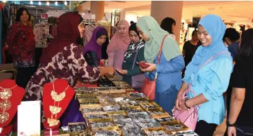  ??  ?? Rosmah (left) entertains patrons at Selangor Pewter based crafts stall.