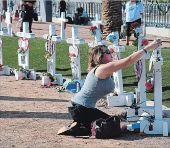  ?? ETHAN MILLER GETTY IMAGES ?? Ashley Schuck of Nevada places a medal she got for running for shooting victim Neysa Tonks in Saturday's Vegas Strong 5K on a cross set up for Tonks on Oct. 1 in Las Vegas, Nevada.