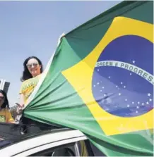  ??  ?? ► Manifestan­tes muestran la bandera de Brasil durante una carrera en apoyo a Jair Bolsonaro.
