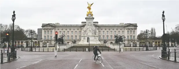  ?? JUSTIN TALLIS / AFP via Gety Images ?? A cyclist rides down the deserted Mall in London, backdroppe­d by Buckingham Palace, as Britain enters a national lockdown on Tuesday.