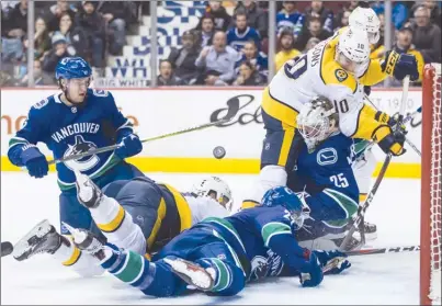  ?? The Canadian Press ?? Vancouver Canucks defenceman Derrick Pouliot, left, watches the puck after Ben Hutton, front right, dove to scoop the puck off the goal line behind netminder Jacob Markstrom to prevent Nashville Predators forwards Colton Sissons (10), Mike Fisher (12)...