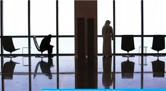  ??  ?? KUWAIT: Men stare at the sea through a window from Al-Hamra Tower in Kuwait City yesterday. — Photo by Yasser Al-Zayyat