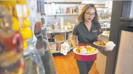  ?? Erik Verduzco Las Vegas Review-journal @Erik_verduzco ?? Lita Harris brings food to customers at lunchtime Thursday at Archi’s Thai Bistro.