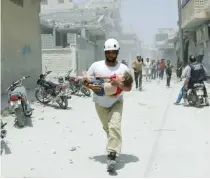  ?? (Khalil Ashawi/Reuters) ?? A CIVIL DEFENSE representa­tive carries an injured girl at a site hit by air strikes in Syria’s Idlib province on Thursday.