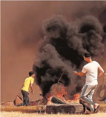  ??  ?? Manifestan­tes palestinos queman neumáticos en una protesta en Gaza