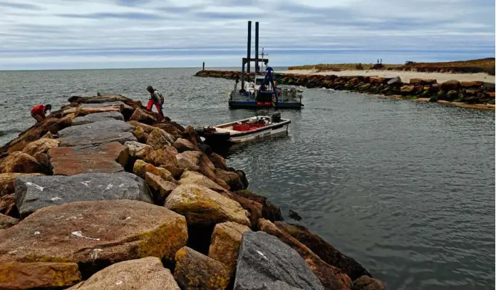  ?? PHOTOS BY DAVID L. RYAN/GLOBE STAFF ?? Above, dredging at the entrance to Allen Harbor in Harwich was bringing in sand. At left, a cutter head dredge.