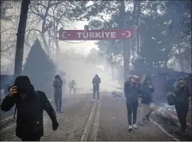  ?? ISMAIL COSKUN — IHA VIA AP ?? Greek border guards use tear gas to try to push back migrants who are trying to enter Greece at the Pazarkule border gate near Edirne, Turkey, on Saturday.